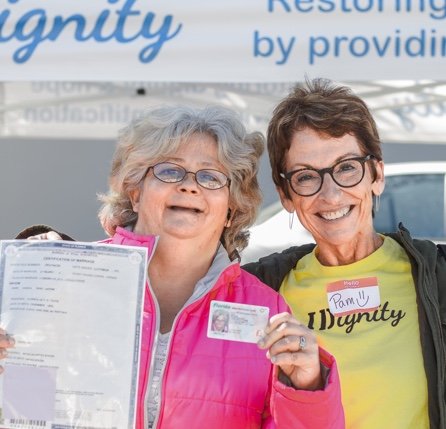 Smiling women with glasses hold up an identification card